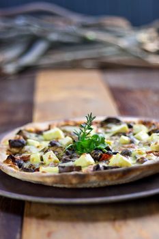 A Rustic Vegetarian pizza laid out on a wooden tray on a wooden table in a pizzeria.