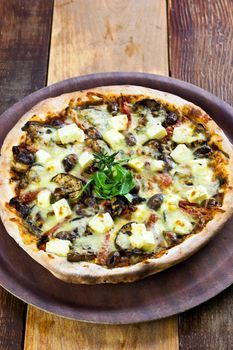 A Rustic Vegetarian pizza laid out on a wooden tray on a wooden table in a pizzeria.