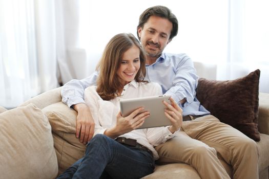 Cheerful couple using digital tablet at home