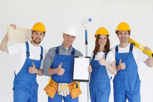 Group of smiling builders in hardhats with tools indoors