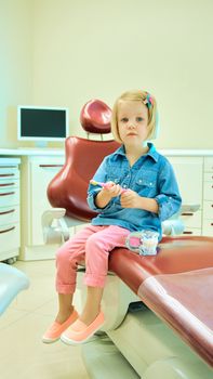 Little blond girl sitting in the dentists office