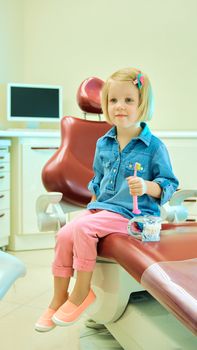 Little blond girl sitting in the dentists office