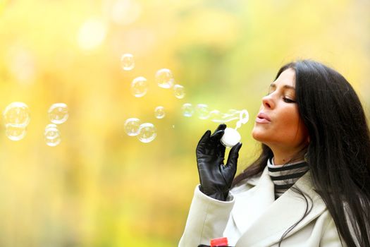 Young Woman Blowing Bubbles on autumn park background