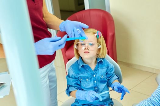 Little girl sitting in the dentists office learning to clean teeth