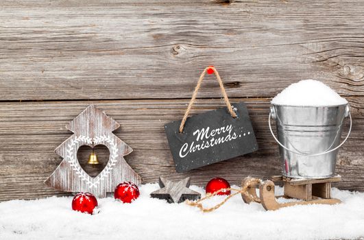 Snow in a bucket on a sled, on wooden background, with Christmas decoration