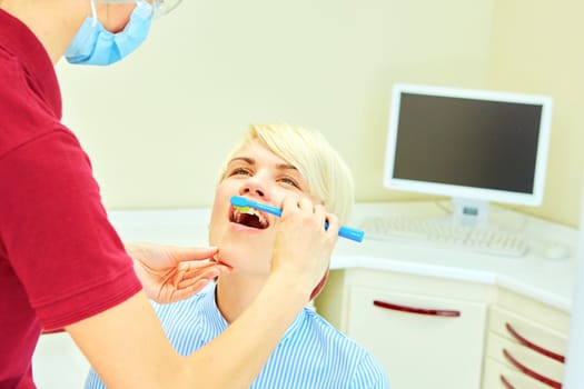 dentist brushing teeth to her patient in dental clinic