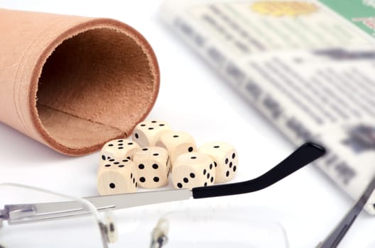 Seven wooden dice, glasses and newspapers in background.