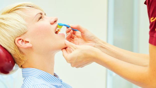 dentist brushing teeth to her patient in dental clinic