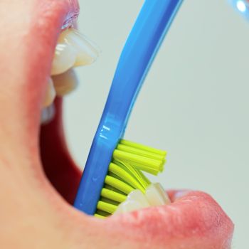 Dentist showing a woman how to brush her teeth. Closeup. Shallow dof
