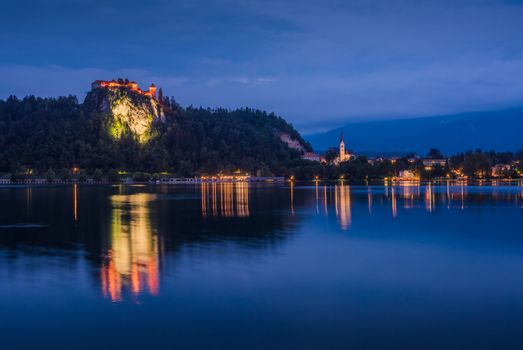 Illuminated Bled Castle at Bled Lake in Slovenia at Night Reflected on Water Surface