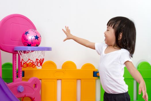 Asian Chinese little girl playing basketball at indoor colourful playground