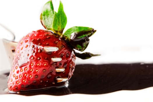 Strawberry on fork with  liquid chocolate on a white background.Horizontal image