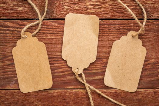 three blank paper price tags with a twine against planks of rustic barn wood