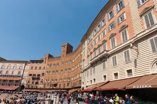 SIENA, ITALY - APRIL 19; Piazza Del Campo a medieval town square, Surrounding heritage buildings that form enclosed piazza busy late morning people and shops on April 19, 2011 in Siena, Italy.