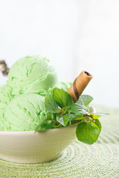 Scoop of mint ice cream in cup on wooden vintage background.