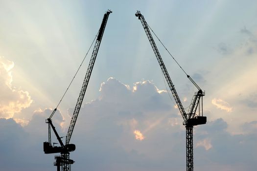silhouette of construction crane with beautiful sunbeam background