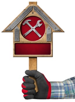 Hand with work glove holding a wooden sign with a meter ruler in the shape of house and a symbol with hammer and wrench. Isolated on white