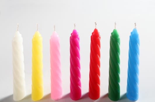 seven colored candles on white background
