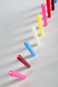 seven cylindrical candles colored on white background