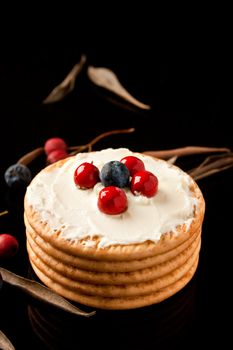  Cookies with cream cheese and blueberries on top  surrounded with berries and dry leaves