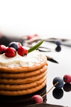  Cookies with cream cheese and blueberries on top surrounded with berries and dry leaves