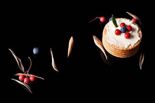  Cookies with cream cheese and blueberries on top surrounded with berries and dry leaves