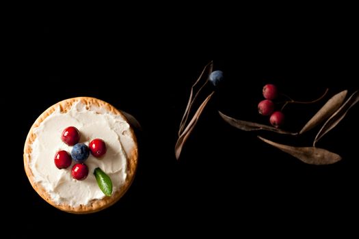  Cookies with cream cheese and blueberries on top surrounded with berries and dry leaves