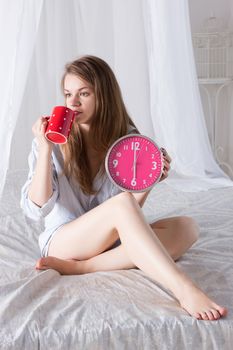 Happy girl  wake up , thumbs up with alarm clock and  coffee cup 6 a.m