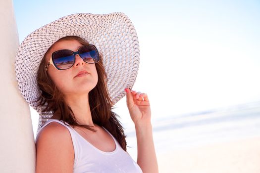 A young white girl in a hat on the beach
