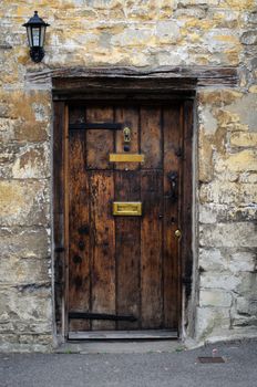 Old wooden door in a Cotswold stone house in the Cotswolds, England, UK.