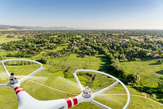 quadcopter drone flying over prairie landscape with city residential area in distance - digital composite image
