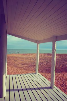White beach house porch with vintage style filter effect and ocean view background.