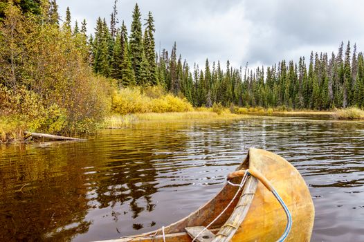 Canoe moored in McGillivray Lake in the Shuswap Highlands in central British Columbia with surrounding trees reflecting on the water