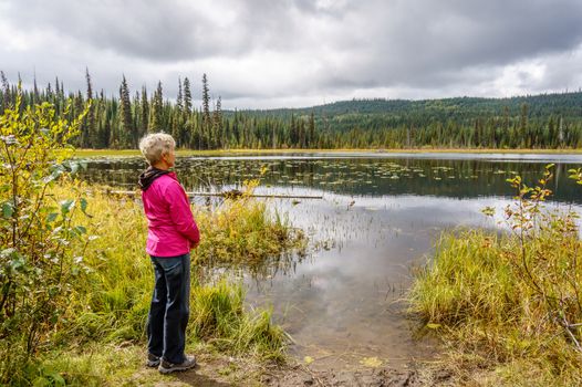 Woman looking over Little McGillivray Lake in the Shuswap Highlands on a cloudy autumn day