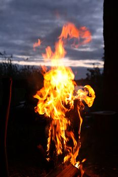 Closeup of burning log against dark evening sky