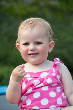 Happy cute little one year old girl outdoor, summer, with pink dress