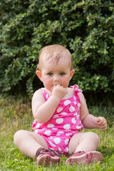 Happy cute little one year old girl outdoor, summer, with pink dress