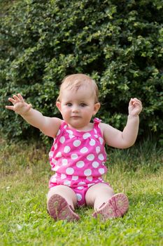Happy cute little one year old girl outdoor, summer, with pink dress