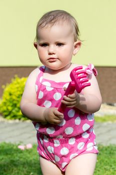 Happy cute little one year old girl outdoor, summer, with pink dress