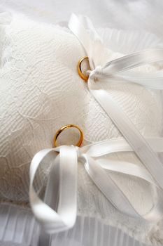 yellow wedding rings on white pillow with tassels