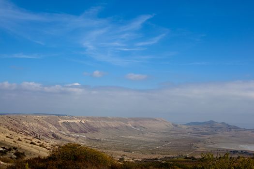 An autumn valley with bushes and blue sky
