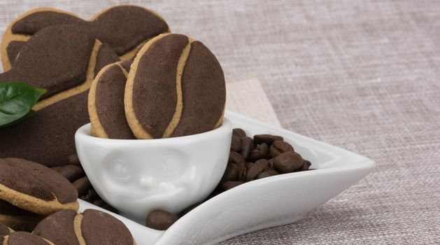 Delicious coffee cookies and coffee beans in a cute cup with facial expressions