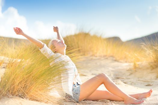 Relaxed woman enjoying freedom and life in beautiful natural environment. Blissful girl raising arms, feeling free, relaxed and happy. Concept of freedom, happiness, enjoyment and natural balance.