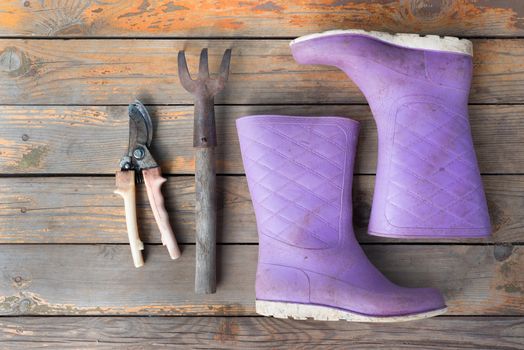 Old wooden texture background with tools and wellingtons, close up view