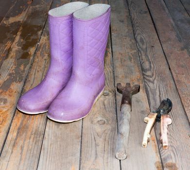 Old wooden texture background with tools and wellingtons, close up view