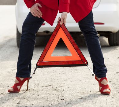 Woman with a red triangle sign on a road
