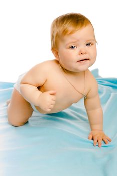 upset baby in diapers on a blue coverlet. Studio