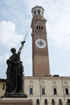 Justice raises his sword toward the tower lamberti, verona italy