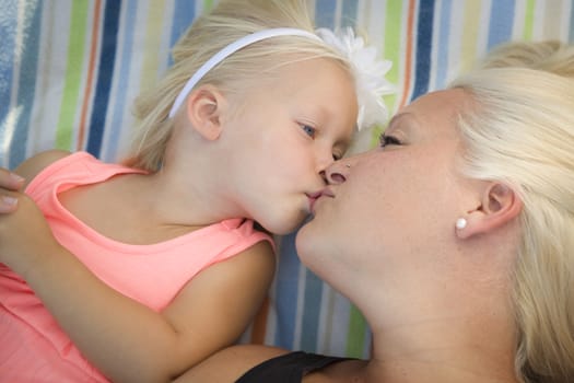 Cute Little Girl Laying on a Blanket Kisses Her Mommy.