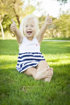 Cute Little Girl with Thumbs Up in the Grass Outside.